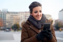 Молодая женщина в зимней одежде использует смартфон на открытом воздухе в Милане Италия — стоковое фото