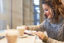Fröhliche Frau liest Reiseführer in einer Cafeteria — Stockfoto