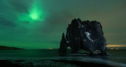 Pintoresca vista de la playa y la formación de rocas bajo las luces del norte del cielo en Hvtserkur Islandia - foto de stock