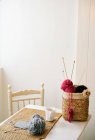 Xícara de chá quente colocado na mesa perto da cesta com fios de tricô e agulhas no quarto acolhedor — Fotografia de Stock