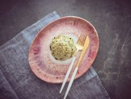 Coltello e forchetta con carciofo fresco intero su piatto di ceramica rosa — Foto stock