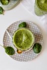 Здоровый зеленый смузи из шпината, авокадо и киви, яблоко и лимон в стекле на узорной тарелке — стоковое фото