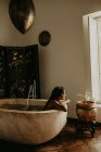 Seitenansicht einer hübschen Frau, die in einem rustikalen Haus badet — Stockfoto
