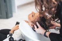 Stylist lavare i capelli alla giovane signora — Foto stock