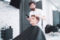 Parrucchiere asciugando capelli a donna — Foto stock