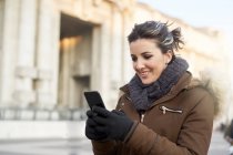 Jeune femme en vêtements d'hiver en utilisant un téléphone intelligent en plein air à Milan Italie — Photo de stock
