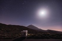 Caravane itinérante dans le désert avec une lune brillante et ciel étoilé — Photo de stock