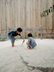 Двоє чарівних афроамериканських хлопців у повсякденному одязі бавляться з піском і проводять час на подвір 