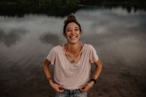 Retrato de mulher sorridente perto da lagoa com água calma no campo — Fotografia de Stock