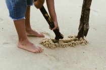 Raccolto ragazzo afroamericano con bastone giocare sulla riva sabbiosa vicino al mare — Foto stock