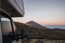 Кемпер припаркований в дикій області на тлі гірського піку і світанку небо в ранок — стокове фото