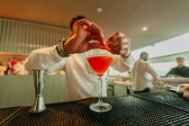 Barman preparing orange cocktail in a bar — Stock Photo