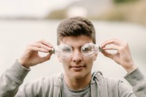 Jovem adolescente com um par de lâmpadas na frente de seus olhos inovação e imaginação conceito — Fotografia de Stock