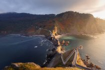 Von oben malerische Landschaft der Insel Gaztelugatxe mit langer Steinbrücke, die bei windigem Tag durch die Küste führt — Stockfoto