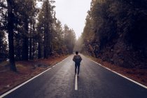 Мужчина путешествует по пустой дороге в лесу — стоковое фото
