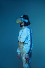 Eccitato giovane donna avendo esperienza di realtà virtuale in luce al neon — Foto stock