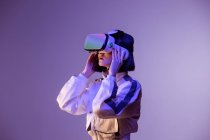 Excited young woman having virtual reality experience in neon light — Stock Photo