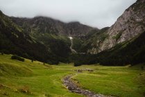 Belle montagne situate intorno a valle calma con erba verde nella giornata nuvolosa in campagna incredibile — Foto stock