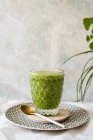 Healthy green smoothie of spinach, avocado and kiwi, apple and lemon in glass on wooden board — Stock Photo