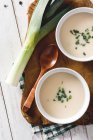 Shoot from above of two bowls of tasty Vichyssoise soups on wooden table with leek — Stock Photo