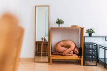 Side view of naked woman nestling inside a wooden cabinet in cozy room at home — Stock Photo