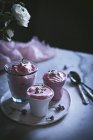 Glasses of sweet strawberry mousse on table with flowers — Stock Photo