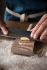 Анонімні жінки готують тісто для домашньої пасти на дерев'яному інструменті в столі на кухні — стокове фото