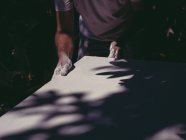 Mãos de artista masculino anônimo espalhando gesso branco áspero na superfície lisa na oficina — Fotografia de Stock
