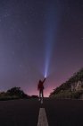 Viaggiatore in giacca rossa con cappuccio in piedi con torcia nella notte stellata — Foto stock