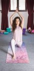 Flexible sportliche Brünette macht Yoga-Pose mit den Händen über dem Kopf und blickt in die Kamera — Stockfoto