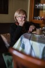 D'en haut femme âgée prenant le petit déjeuner assis à la table — Photo de stock