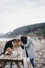 Молода жінка обіймає сумного собаку на березі моря — стокове фото