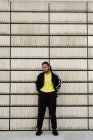 Junger afrikanisch-amerikanischer Typ in trendiger Sportbekleidung blickt in die Kamera, während er in der Nähe von Betonblöcken auf der Stadtstraße steht — Stockfoto