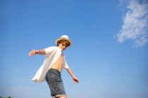 From above attractive boy in hat and unbuttoned shirt standing with open hands — Stock Photo
