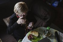 Старша приваблива жінка приймає ліки з пігулки перед сніданком — стокове фото