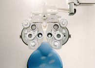 Moderna attrezzatura di prova visione e sedia contro parete bianca in ufficio ottico in clinica — Foto stock