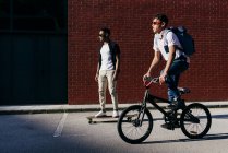 Junge afrikanisch-amerikanische Männer auf Fahrrad und Skateboard — Stockfoto