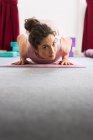 Flexible sportive concentrated brunette in sportswear doing lying yoga pose on mat — Stock Photo