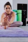 Jovem atlética morena praticando ioga pose enquanto sentado no tapete em estúdio — Fotografia de Stock