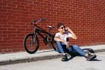 Молодой счастливый черный мужчина разговаривает смартфон на велосипеде — стоковое фото