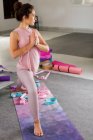 Schlanke Brünette in bequemer Sportbekleidung, die Hände in namaste Position haltend, während sie Yoga im Studio praktiziert — Stockfoto