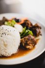 Preparato deliziose costolette di maiale caldo con riso e verdure sane come cetriolo e cipolla sul piatto nel ristorante asiatico — Foto stock