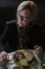 De cima mulher idosa tomando café da manhã enquanto se senta à mesa — Fotografia de Stock