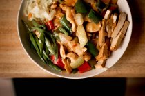 Миска вкусного вегетарианского блюда с овощами на деревянном столе — стоковое фото