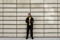 Jeune homme afro-américain en vêtements de sport à la mode regardant la caméra tout en se tenant près de blocs de ciment sur la rue de la ville — Photo de stock