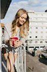 Молода жінка з чашкою на терасі — стокове фото