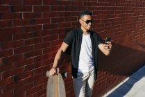 Young black man with long board speaking on phone — Stock Photo