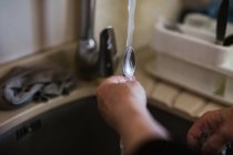 Imagem cortada de mulher de pé perto da pia e colher de lavar com sabão na cozinha em casa — Fotografia de Stock