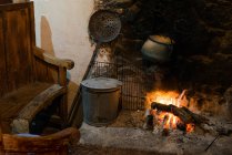 Comfortable beautiful kitchen with fireplace and housewares like pan and grid of old warm village house — Stock Photo