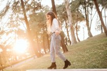 Junge Frau in lässigem Outfit streckt Arme aus und balanciert an sonnigem Tag im Park über Zaun — Stockfoto